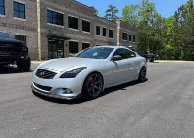 Lowered silver Infiniti G37 coupe, gunmetal aftermarket wheels, red calipers—Automotive Expressions styling at brick office