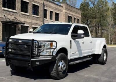 Automotive Expressions white Ford Super Duty dually crew cab with heavy-duty grille guard, off-road tires, truck accessories