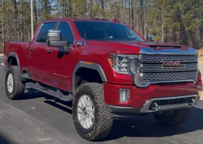 Automotive Expressions red GMC Sierra HD 4x4, lifted with off-road tires, chrome grille, tow mirrors, crew cab blacktop