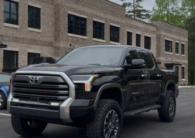 Black Toyota Tundra with custom vinyl door graphics, off-road tires at brick office, Automotive Expressions